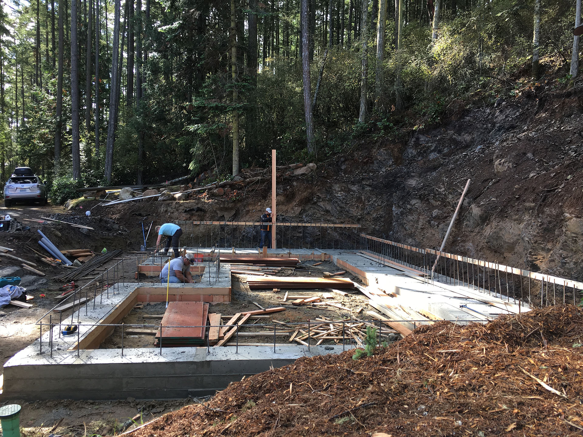 In-progress photo of a foundation pour at a new construction site surrounded by trees.