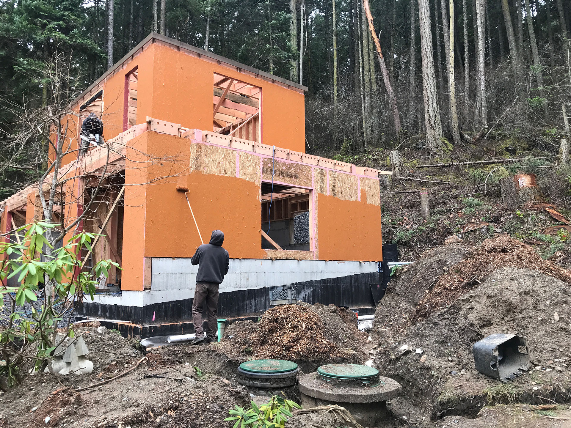 True Bearing Built employee applying a liquid water-resistive barrier to the outside of a in-construction home.